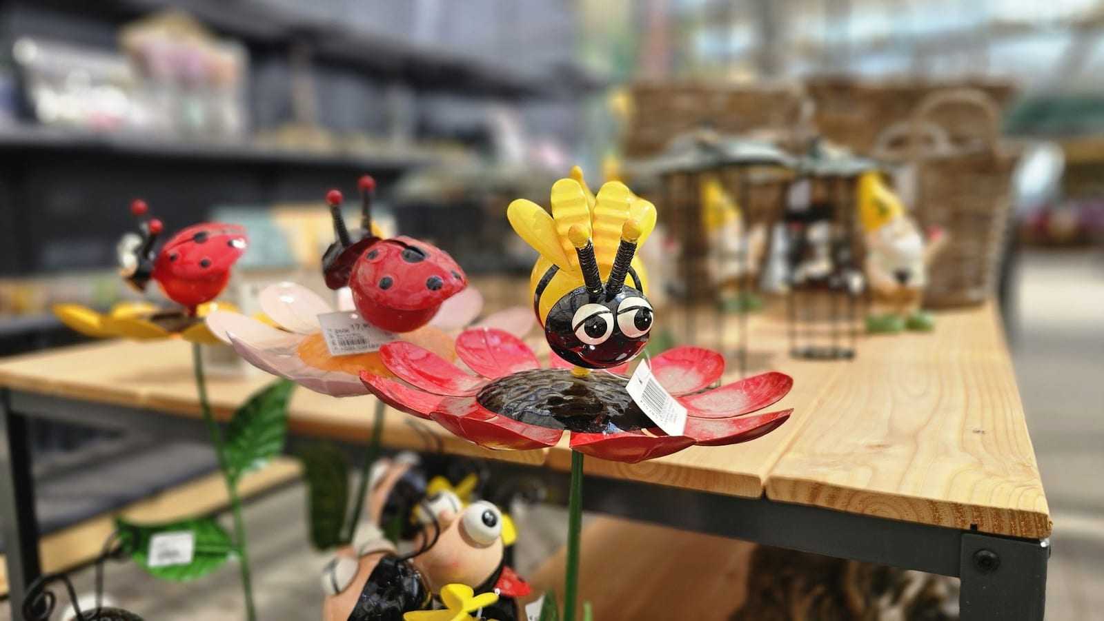 Deko-Insekten aus Metall, Marienkäfer, Biene und Schmetterling, auf einem Holztisch