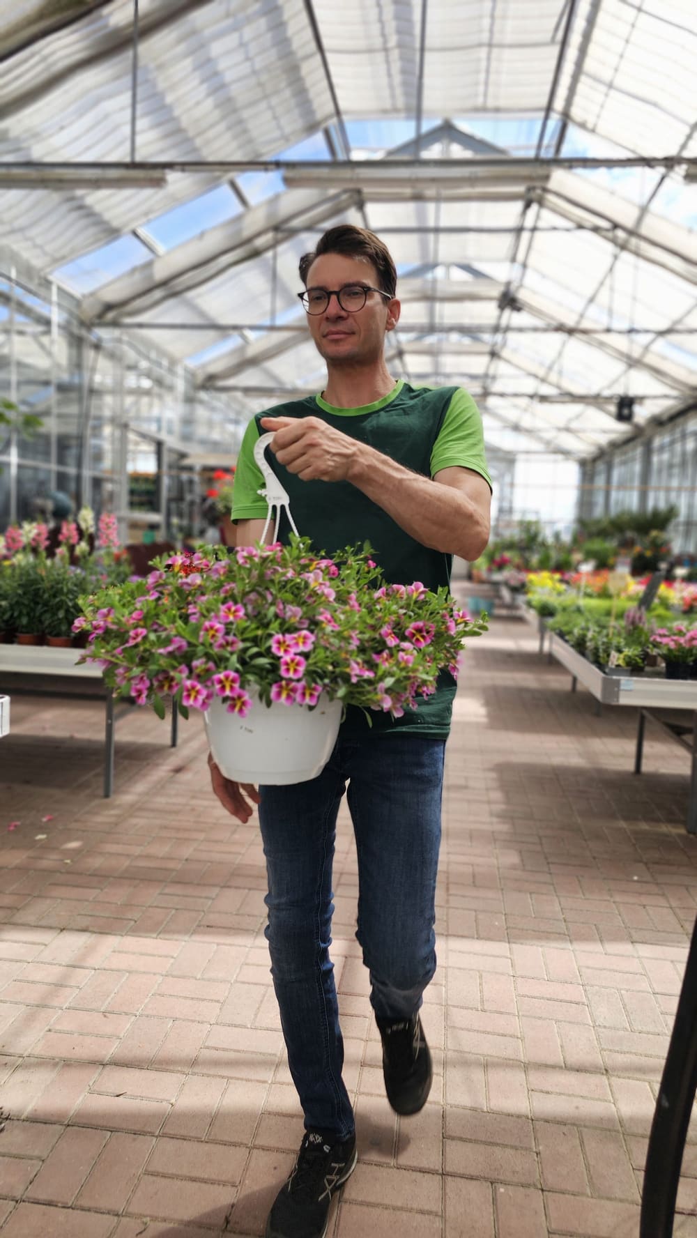 Mitarbeiter der Saale-Baumschule präsentiert eine blühende Blumenampel